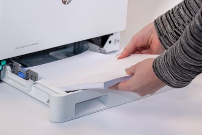in eine Drucker-Papierkassette wird Druckerpapier eingelegt