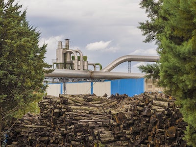 Papierfabrik mit Holz im Vordergrund